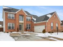 Beautiful two-story brick home with a two-car garage and snow-covered yard at 8694 Emerald Blvd, McCordsville, IN 46055