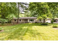 Charming stone house with a lush green lawn and mature trees, creating a serene and inviting curb appeal at 9228 Westfield Blvd, Indianapolis, IN 46240