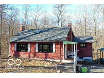 Charming red home with a brick chimney and gray roof nestled amongst mature trees at 9464 N State Rd 135, Morgantown, IN 46160