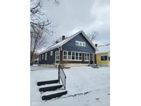 Charming blue bungalow with brick foundation, multiple windows, and snow-covered yard at 2309 N Dearborn St, Indianapolis, IN 46218