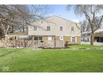 Two-story townhome featuring a brick facade, white siding, a fenced yard, and a well-maintained lawn at 3986 Braddock Rd, Indianapolis, IN 46268