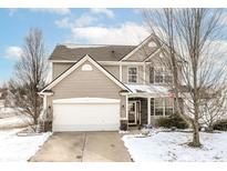 Charming two-story home featuring a two-car garage and a welcoming front porch, partially covered in snow at 5700 Scotland St, Indianapolis, IN 46234