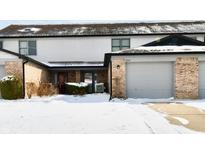 Two-story townhome featuring a one-car garage, brick accents, neutral siding and snow-covered yard at 9247 Backwater Dr, Indianapolis, IN 46250