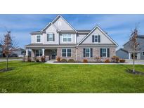 Charming two-story home featuring a manicured lawn, brick accents, and a welcoming front porch at 11856 Springtide Ln, Fishers, IN 46037