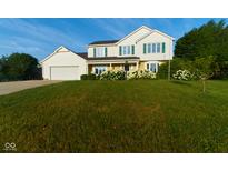 Traditional two-story home with white siding, green shutters and a well-manicured lawn and landscape at 13060 Wembly Cir, Carmel, IN 46033