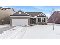 Charming brick home with an attached two-car garage and a snow-covered front yard at 293 Carrick Glen Blvd, Pendleton, IN 46064