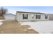 Charming single-story home with grey siding, black shutters, paved driveway and a detached one car garage at 3331 Fall Valley Dr, Columbus, IN 47203