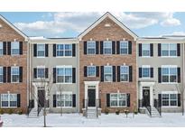 Exterior view of townhomes featuring a mix of brick and gray siding with black shutters and snow-covered lawns at 6965 Equality Blvd, Carmel, IN 46033