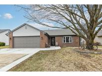 Charming brick home featuring a well-kept lawn, attached garage, and beautiful tree in front at 7344 Quartz Rock Rd, Indianapolis, IN 46236