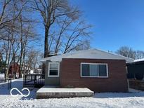 Cozy home exterior with brick siding, snow-covered yard, and inviting deck area at 7897 Hotze St, Indianapolis, IN 46259