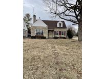 Charming stone home featuring red shutters, a well-maintained lawn, and mature landscaping at 950 Ellenberger Pkwy West Dr, Indianapolis, IN 46219