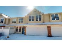 Inviting townhouse with a two-car garage, set against a sunny winter backdrop, showcases appealing curb appeal at 9541 Brightwell Dr, Indianapolis, IN 46260