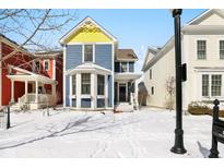 Charming blue two-story home featuring a yellow gable, bay window, and covered front porch at 12916 Tradd St, Carmel, IN 46032