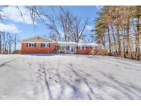 Cozy brick home featuring a quaint front porch and a snow-covered front yard at 3232 Pinecrest Rd, Indianapolis, IN 46234
