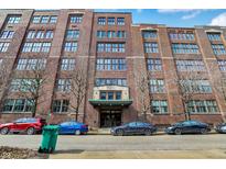 A stunning exterior shot showcases a brick apartment building on a sunny day with cars lining the street at 430 N Park Ave # 309, Indianapolis, IN 46202