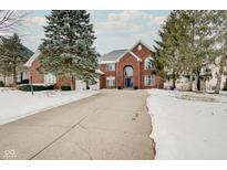 A brick two-story house featuring a large driveway with some snow, and manicured trees, offering a lovely curb appeal at 4754 Austin Trce, Zionsville, IN 46077