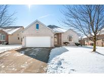Charming brick home featuring an attached garage, a well-maintained lawn, and a sunny winter landscape at 6045 Sheridan Dr, Columbus, IN 47203