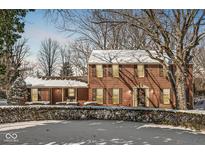 Traditional brick home with snow, a manicured lawn, and mature trees, offering classic charm and curb appeal at 925 Forest Dr, Anderson, IN 46011