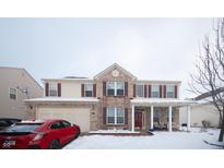 Charming two-story home with a brick facade, covered porch, and attached two-car garage on a snowy winter day at 1136 Meriman Dr, Greenwood, IN 46143