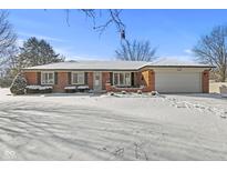 Charming brick home featuring a two-car garage, well-maintained landscaping, and a welcoming front porch at 7609 E Stop 11 Rd, Indianapolis, IN 46259