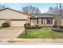 Charming brick home featuring a two-car garage, manicured lawn, and welcoming front entrance at 8429 Quail Hollow Rd, Indianapolis, IN 46260