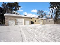 View of the home's exterior featuring a large detached garage with three bays and snow-covered ground at 9800 N Gasburg Rd, Mooresville, IN 46158