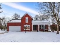 Charming brick home with a two-car garage, covered porch, and snow-covered front yard at 10351 Dolphin Ln, Indianapolis, IN 46256