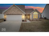 Charming brick house with a two-car garage and a well-manicured lawn during sunset at 1125 Blue Bird Dr, Indianapolis, IN 46231
