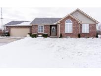 Charming brick home with a manicured lawn, complemented by snow-covered landscaping at 4220 S Danita Ct, New Palestine, IN 46163