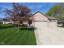 Charming brick home with a three-car garage and a beautifully landscaped front yard and mature tree at 11 Stratford Way, Danville, IN 46122