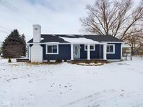 Charming single-story home featuring a brick chimney, blue siding, and a covered front porch at 1902 Silver St, Anderson, IN 46012