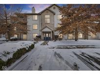 Charming multi-story condo with a striking blue door, complemented by a neatly landscaped yard covered in a blanket of snow at 240 Legends Creek Pl # Apt 205, Indianapolis, IN 46229