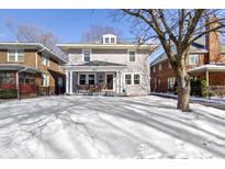 Charming two-story home with inviting front porch and snowy front yard, perfect for a Gathering at 4805 N Park Ave, Indianapolis, IN 46205