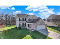 Charming two-story home featuring a brick facade and well-maintained lawn with mature trees against a blue sky at 5147 Nicodemus Dr, Plainfield, IN 46168