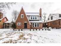 Charming brick two-story home featuring a classic design and snow-covered front yard at 5715 N Delaware St, Indianapolis, IN 46220