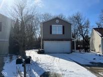 Two-story home featuring an attached garage and a snow-covered driveway and yard at 6534 Redland Way, Indianapolis, IN 46217