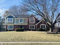 Charming two-story brick home with a well-manicured lawn and mature trees at 676 Woodbine W Dr, Carmel, IN 46033