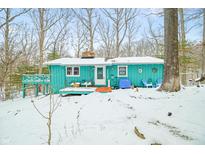 Charming turquoise home featuring an inviting deck and winter wonderland views at 7166 N Oak Ridge Rd, Morgantown, IN 46160