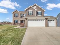 Charming two-story home featuring a three-car garage, brick and vinyl siding, and a well-maintained lawn at 976 Cherry Tree Ln, Greenwood, IN 46143