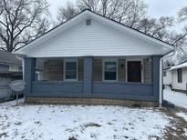 Charming single-story home with a covered front porch, stone accents, and wintery landscaping at 1105 Winfield Ave, Indianapolis, IN 46222