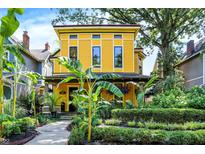 Charming yellow two-story home boasts beautifully landscaped front yard and inviting front porch at 1409 N Park Ave, Indianapolis, IN 46202