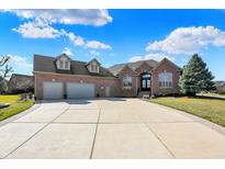 Attractive brick house boasting a spacious driveway and a three-car garage on a lush, green lawn at 2110 Cheviot Ct, Greenwood, IN 46143