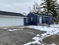 Exterior view of a blue house with a two-car garage on a cloudy day at 6018 Ivanhoe St, Indianapolis, IN 46219