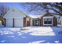 Charming home featuring a two-car garage and brick accents, set against a snowy landscape at 10953 Mount Vernon N Trl, Indianapolis, IN 46229