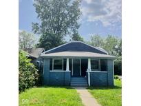 Charming home features a blue painted brick exterior, covered front porch, and landscaped yard at 1165 W 34Th St, Indianapolis, IN 46208