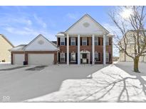 Beautiful brick two-story home with stately white columns, a three-car garage, and a snow-covered lawn at 12773 Broncos Dr, Fishers, IN 46037