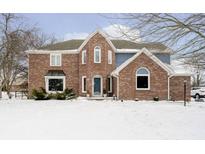 Charming two-story brick home with lovely architectural details and a snowy front yard at 13895 Silver Stream Dr, Carmel, IN 46032