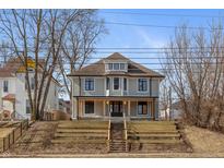 Beautiful two-story home with inviting front porch, landscaped stairs, and neutral siding against a blue sky at 2828 N Illinois St, Indianapolis, IN 46208