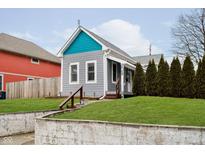 Charming home with gray siding, teal accent, updated windows, and a well-maintained front yard at 308 Sanders St, Indianapolis, IN 46225
