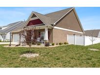 Charming brick home with a well-manicured lawn, white fence, and inviting front porch at 3629 S Meadows Ln, New Palestine, IN 46163